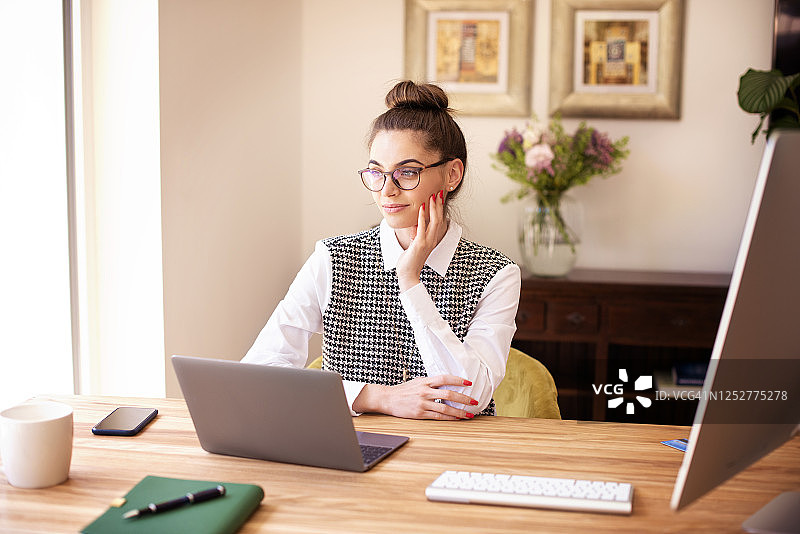 在家坐在桌边使用笔记本电脑、正在做白日梦的思考中的女人图片素材