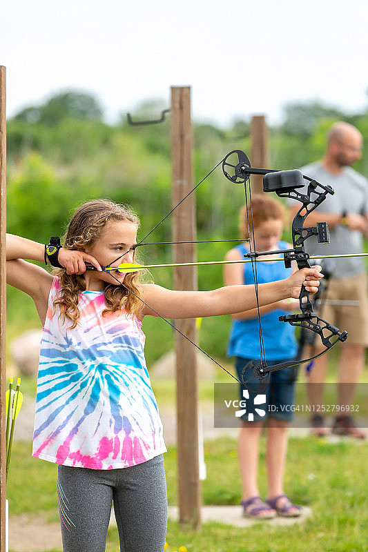 两个女孩和爸爸在户外射箭场练习图片素材