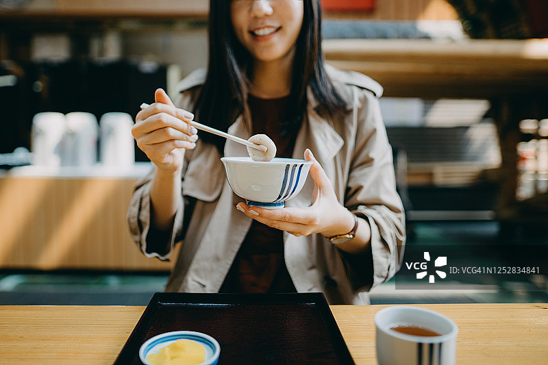 年轻亚洲女游客在日式咖啡馆享用红豆年糕甜品图片素材