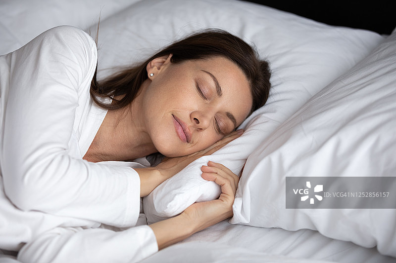 安静的年轻女人在舒适的床上休息睡觉图片素材