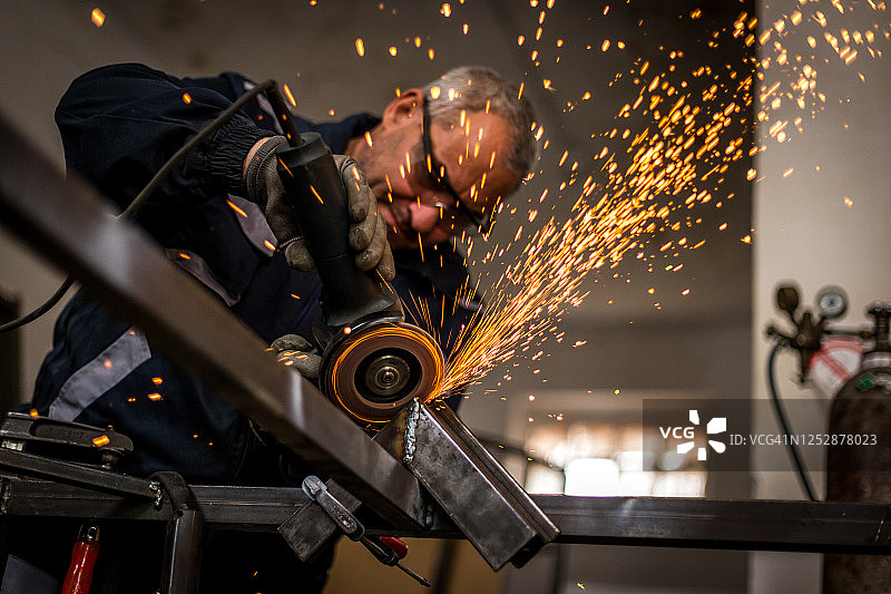年长的男人研磨金属结构图片素材