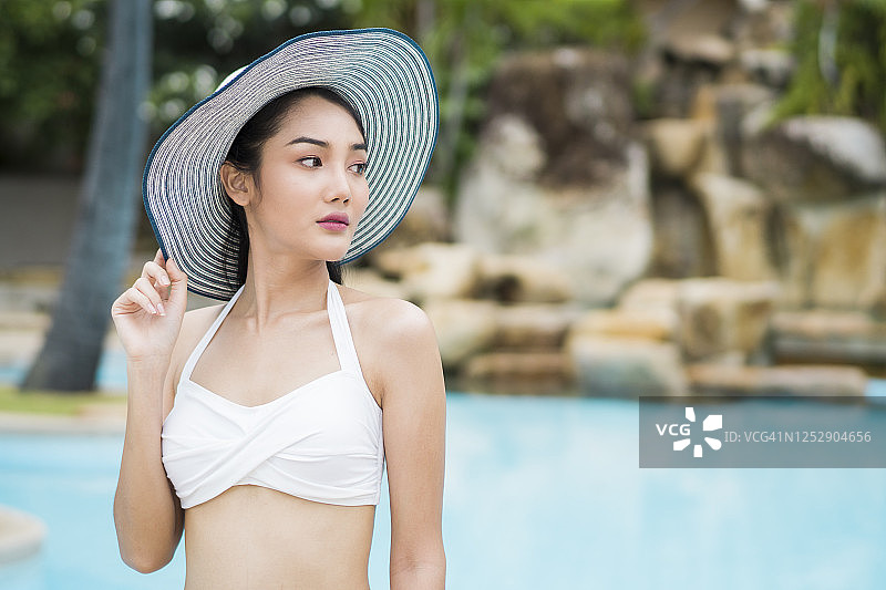 年轻女人在晴天于游泳池里喝饮料图片素材