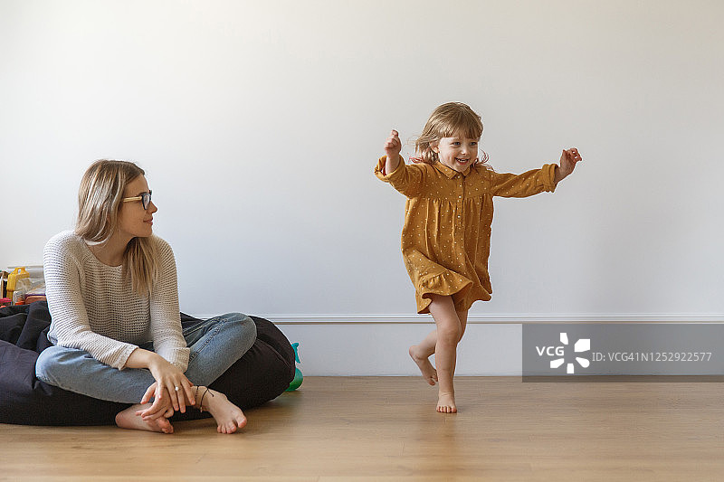 小女孩在微笑的母亲面前跳舞图片素材