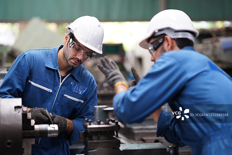 工程师指导新学员进行机械操作和工业设备维护培训图片素材