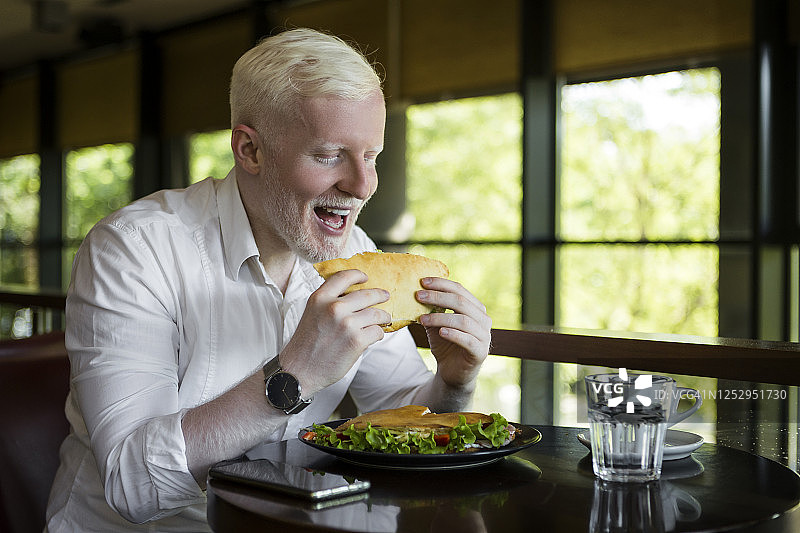 在餐厅用餐的年轻白化病男子图片素材