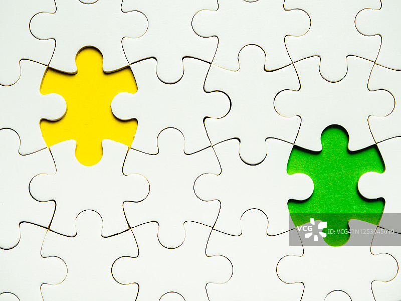 黄色和绿色背景上缺少一块的白色拼图图片素材
