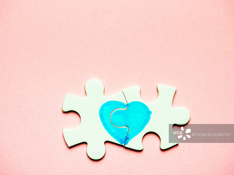 粉色背景上绘有心形的白色拼图块图片素材