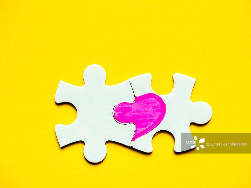 黄色背景上绘有爱心的白色拼图：单恋概念图片素材