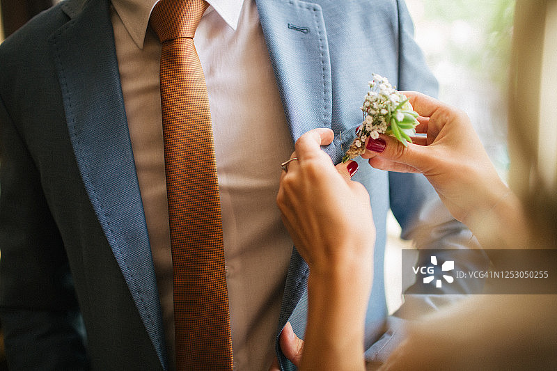 新娘为新郎蓝色西服佩戴鲜花图片素材