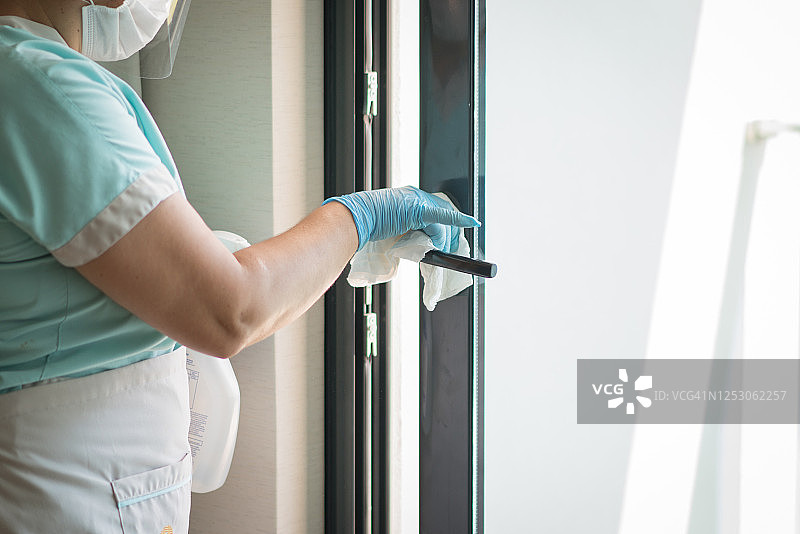 女佣清洁门把手，佩戴口罩图片素材