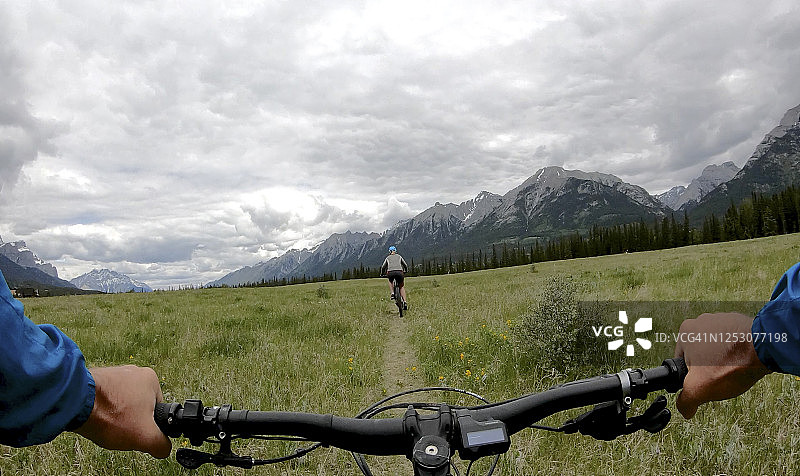 山地自行车车把视角：女子在狭窄的山路上骑行图片素材