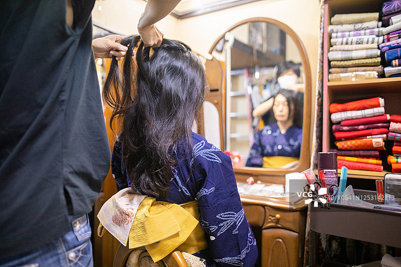 身穿浴衣的日本女人正在接受和服租赁店员的妆发服务图片素材
