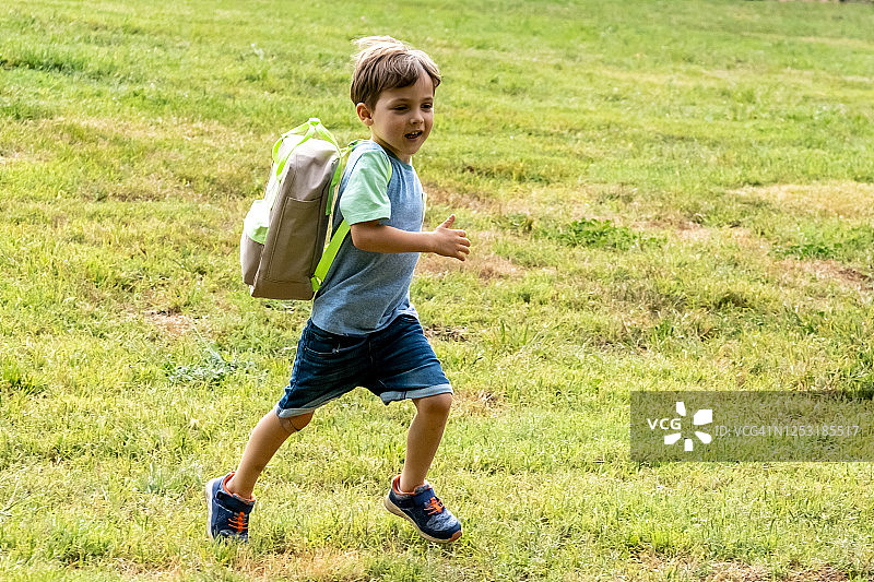 背着背包跑向学校的微笑男学生图片素材