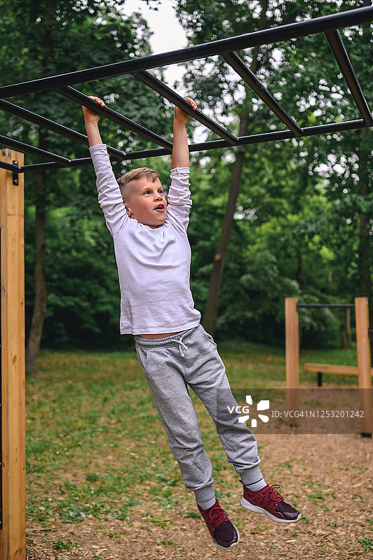 在单杠上荡秋千的男孩图片素材