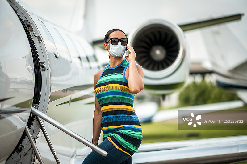 戴口罩墨镜打电话的女性贵宾登上私人飞机图片素材
