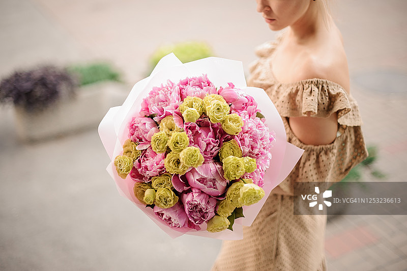 年轻女人手捧粉色牡丹和绿色花束图片素材