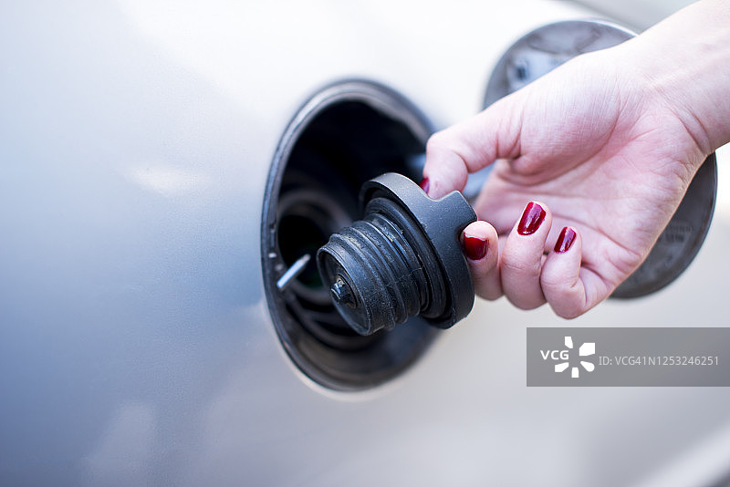 年轻女子手持汽车油箱盖特写图片素材