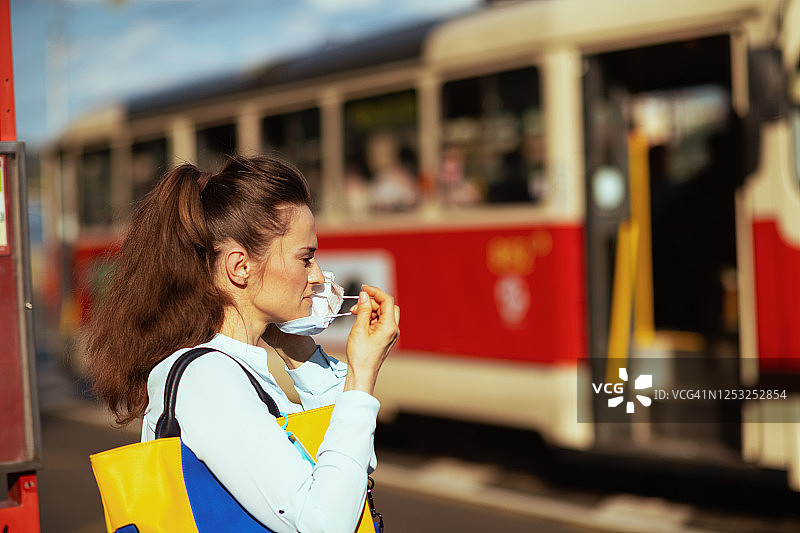 佩戴医用口罩的优雅女性在电车站图片素材