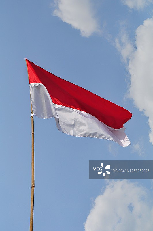 在蓝色天空背景下飘扬的印尼国旗图片素材