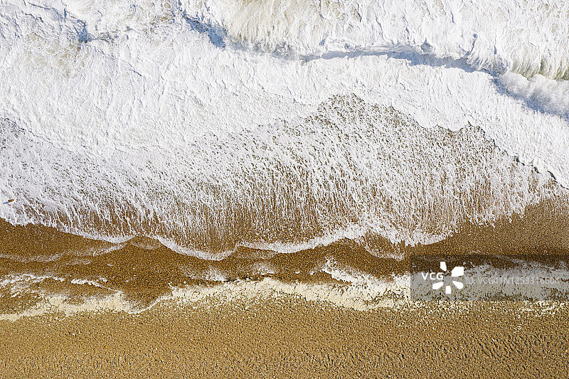 无人机视角下的海浪拍打在卵石滩上图片素材