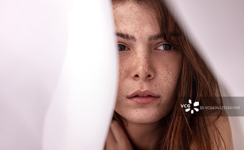 白色织物下有雀斑的年轻女子肖像图片素材