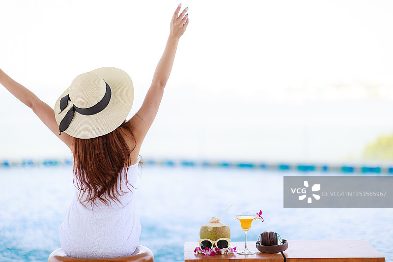 在豪华酒店泳池边放松的亚洲女子。假日和度假概念图片素材