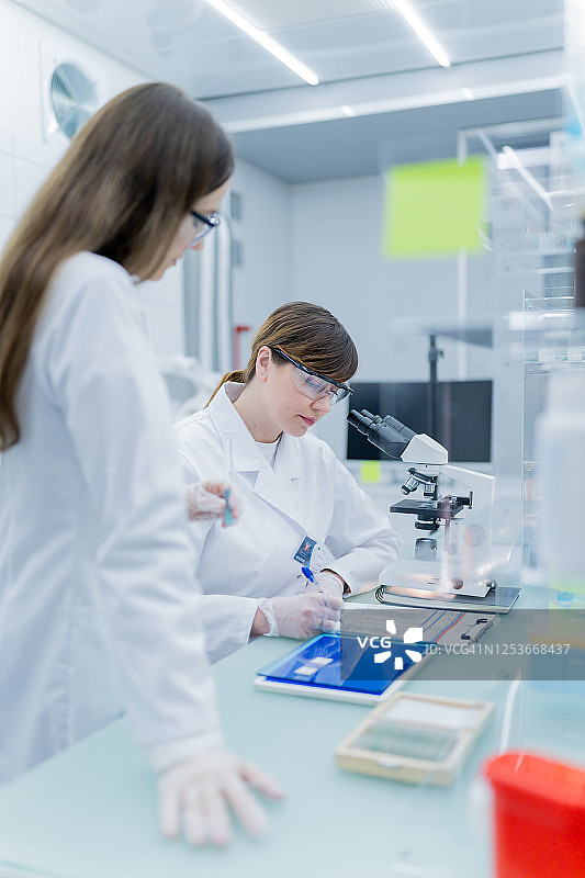 女科学家做笔记，背景是带有数据的电脑显示器图片素材