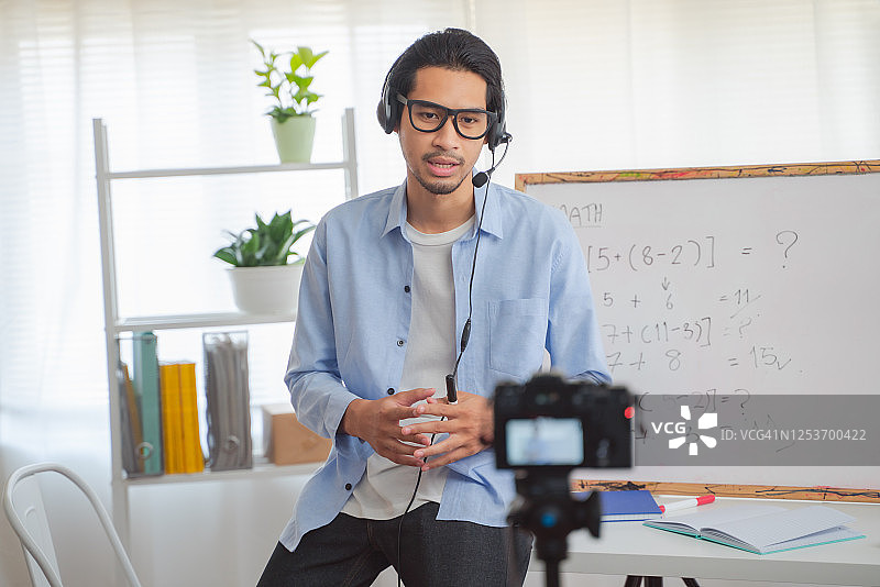 亚洲男人在线教授数学，微笑的女教师录制数学课程Vlog，适合家庭教学图片素材
