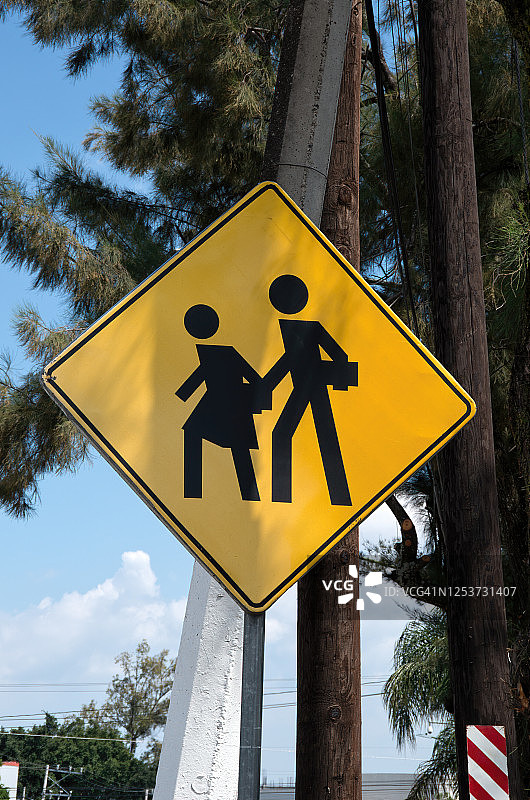 小学生在交通警告标志前过马路图片素材