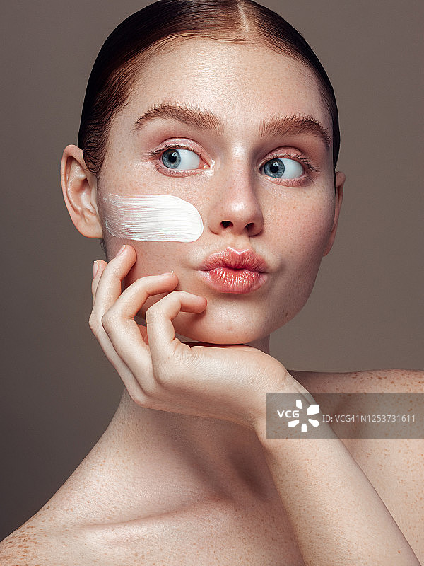 年轻女孩在脸上涂抹乳霜图片素材