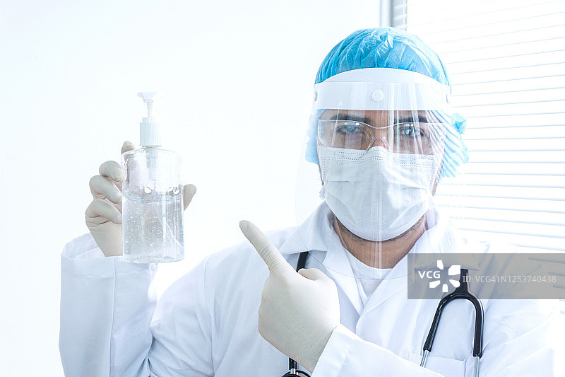 医生穿戴个人防护装备，并指向免洗洗手液图片素材