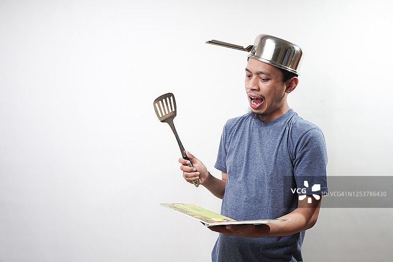 亚洲男人手持锅铲和食谱图片素材