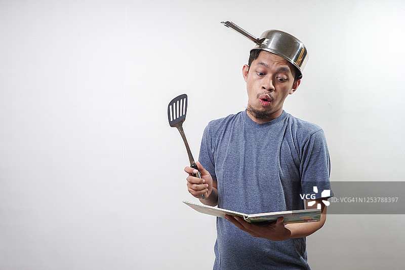 亚洲男人手持锅铲和食谱图片素材