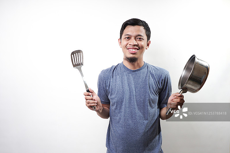 拿着铲子和炒锅的亚洲男人图片素材