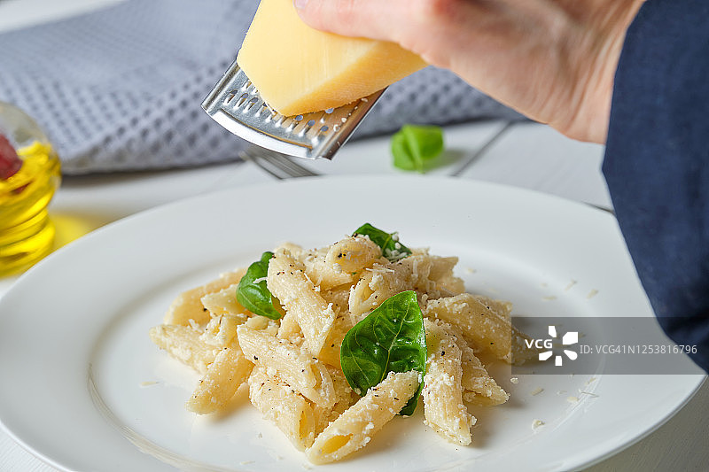 在家烹饪奶油罗勒意面：研磨帕尔马干酪图片素材