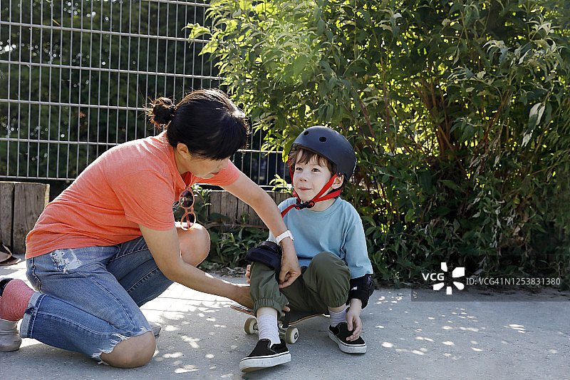 母亲帮儿子戴滑板护膝图片素材