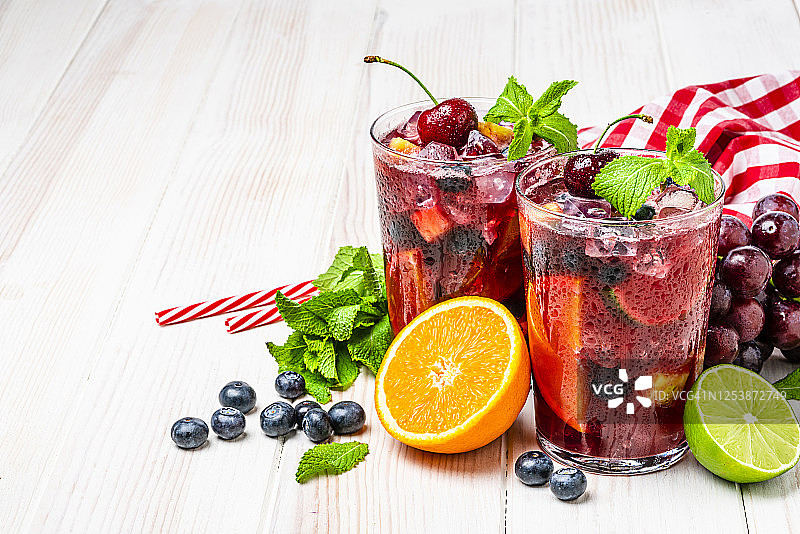 白色桌子上放着两杯冰镇清爽的桑格利亚汽酒和水果，含复制空间图片素材