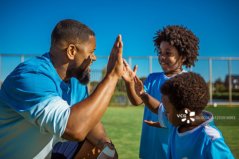 黑人父亲和儿子们在足球场上训练图片素材
