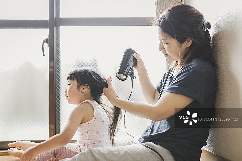 母亲用吹风机吹干女儿的头发图片素材