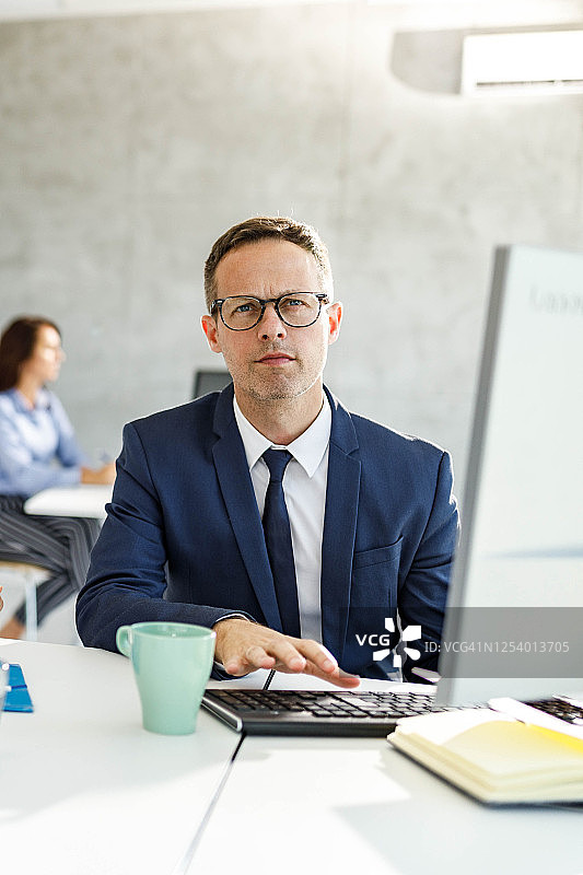 中年商人在办公室使用台式电脑工作图片素材