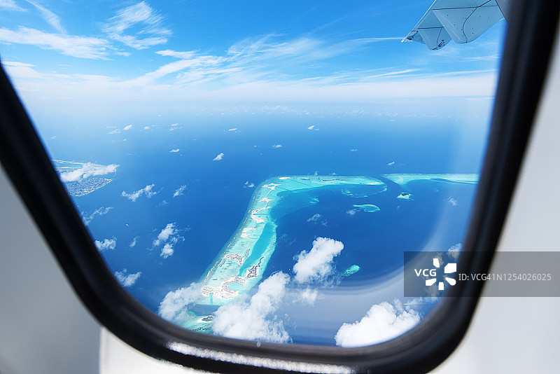 飞机舷窗外的热带岛屿和绿色泻湖景观图片素材