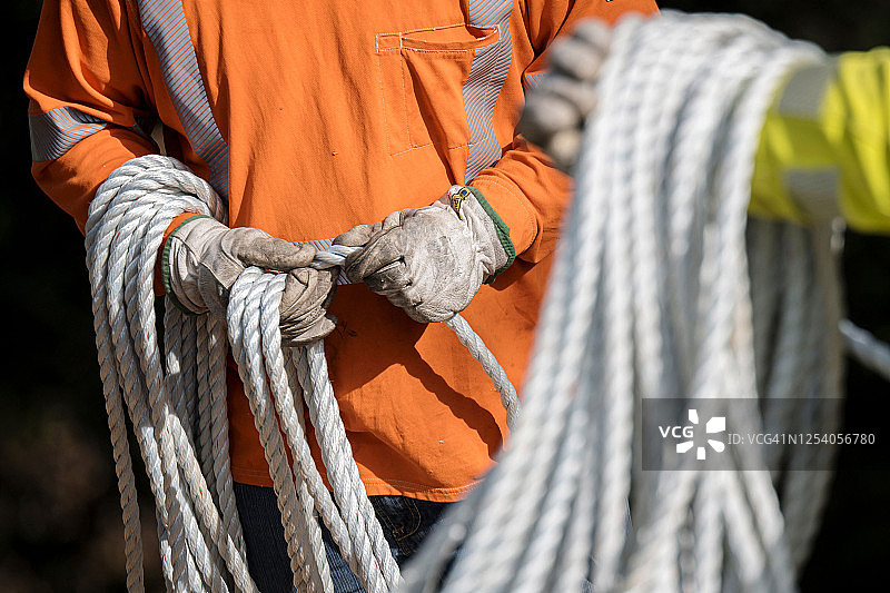 工人拿着一卷绳索图片素材