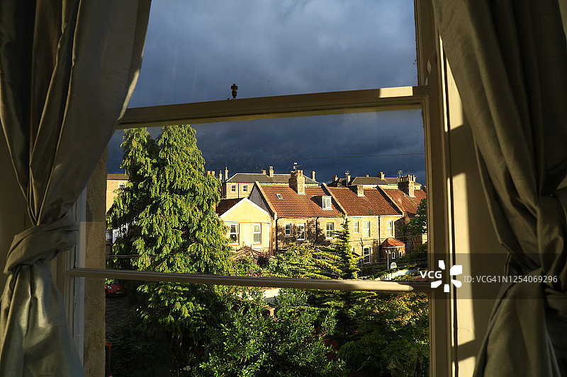 透过窗户看到的维多利亚建筑立面与日落时分的黑暗天空图片素材