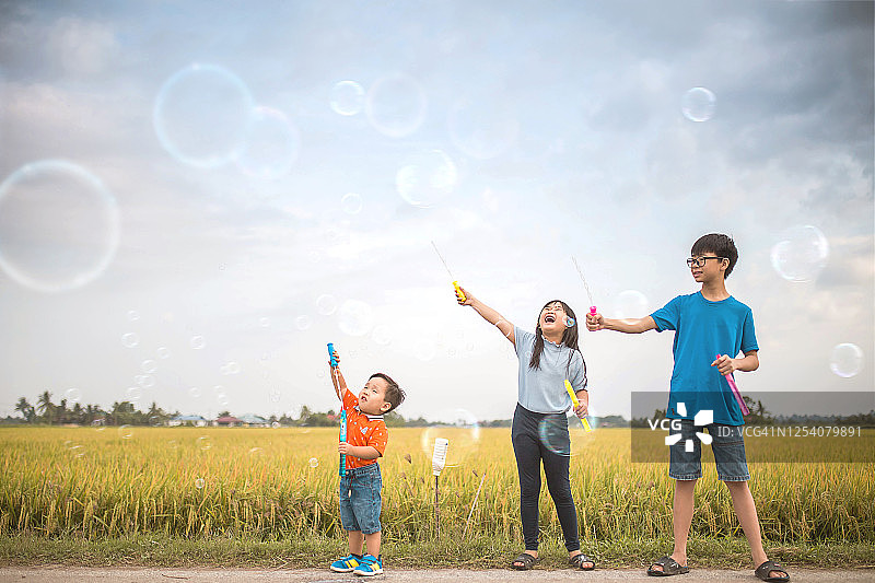 三个中国亚洲儿童在稻田里玩肥皂泡图片素材