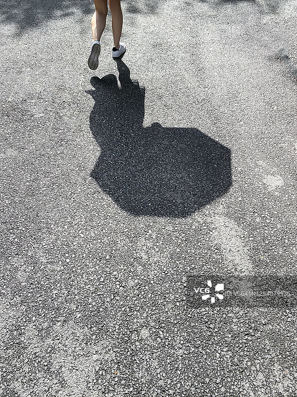 走在路上，阳光下留下影子的女人图片素材