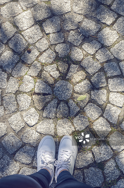 站在鹅卵石街上的女人的低剖面图片素材