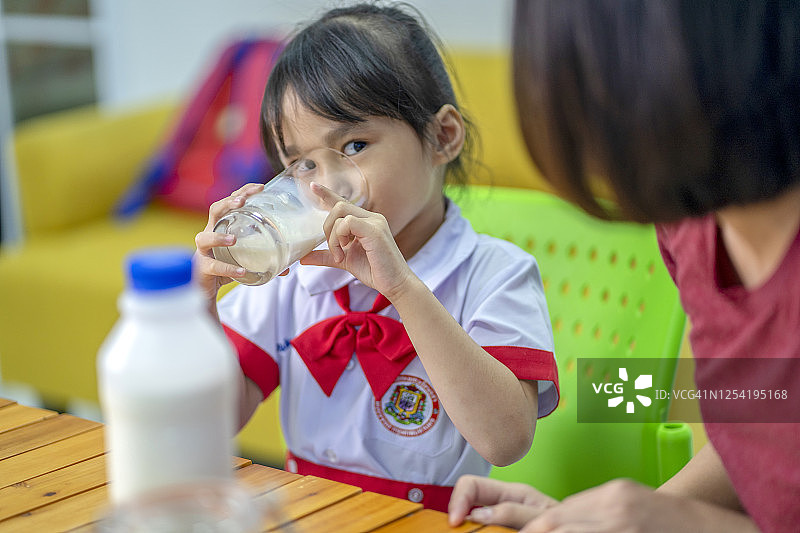 亚洲可爱女学生早上在家上学前喝一杯牛奶图片素材