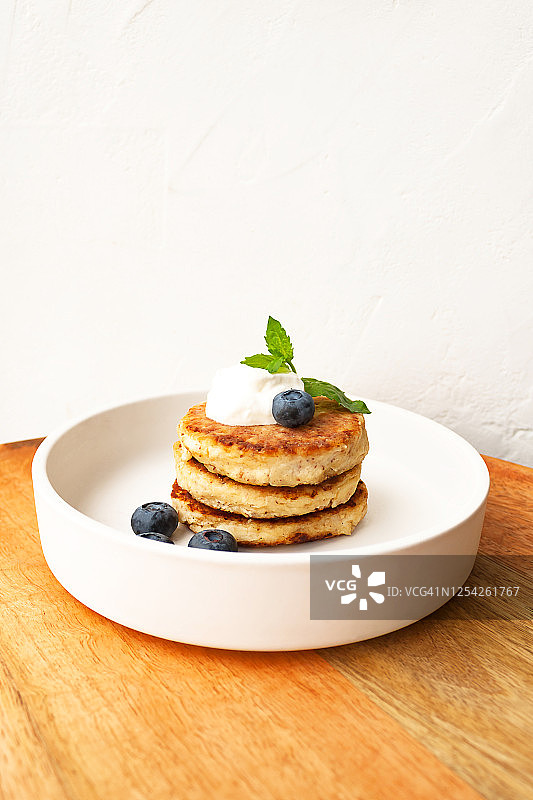 乡村奶酪薄饼或凝乳油炸饼，搭配酸奶油、薄荷叶和蓝莓图片素材