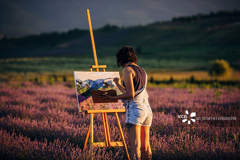 在日落时分薰衣草田里绘画的女画家图片素材