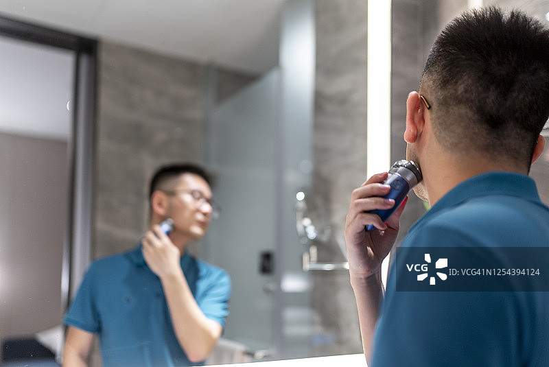 亚洲男人在镜子前刮胡子图片素材